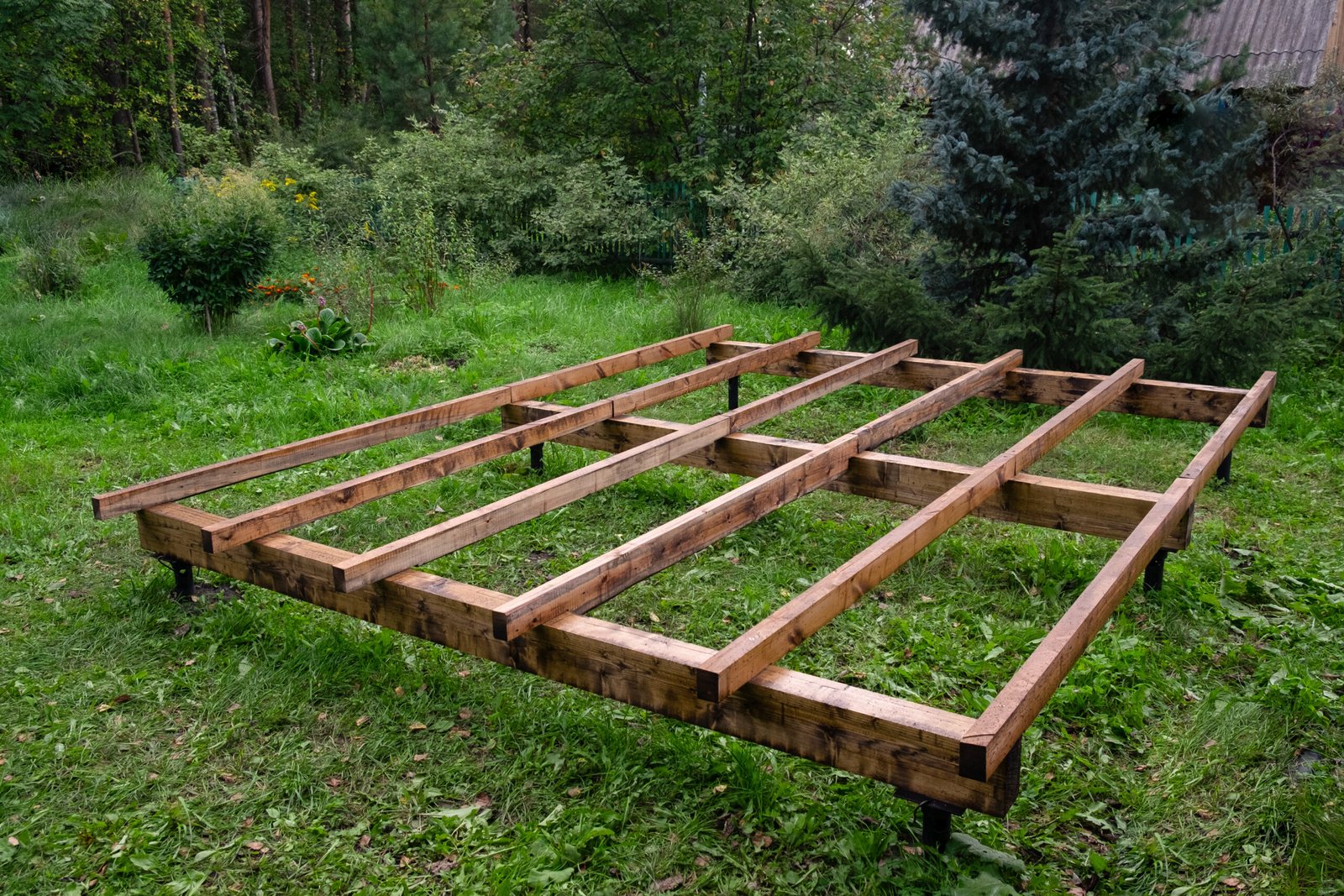 The foundation of a wooden frame house is on screw metal piles